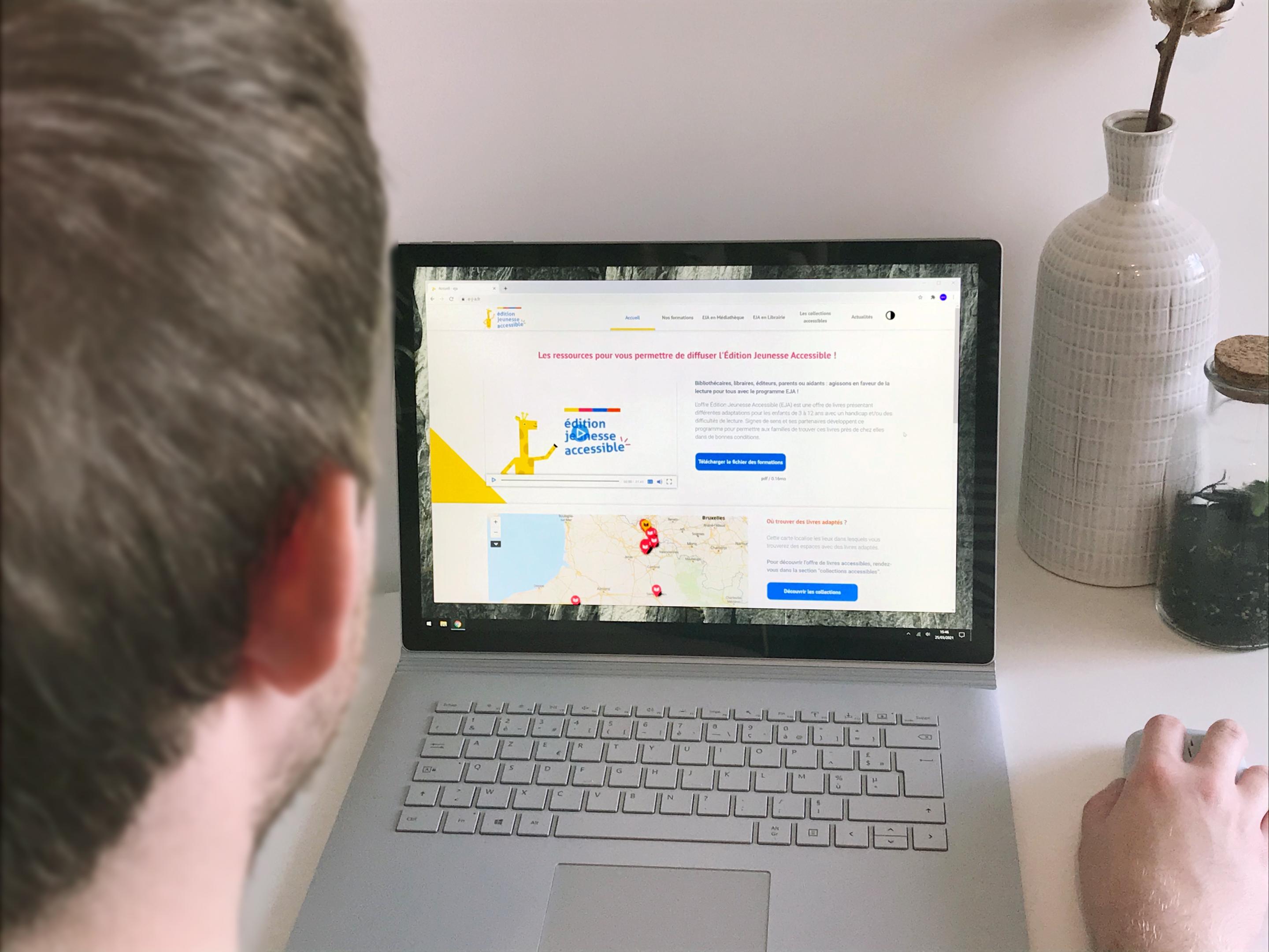 Le nouveau site Edition Jeunesse Accessible Personne qui regarde le site Edition Jeunesse Accessible sur ordinateur