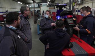 Photo d'illustration du projet Pragmatic : un groupe de personnes dans un garage autour d'un scooter.